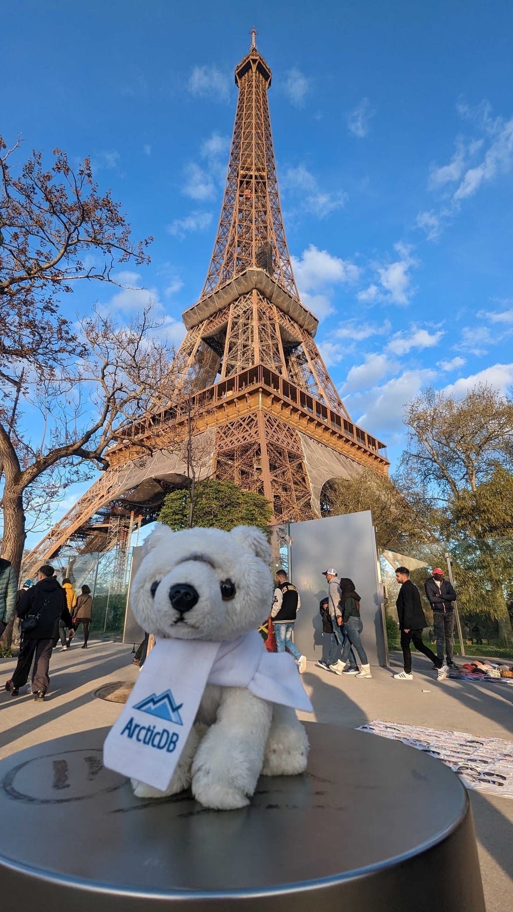 Peluche de oso polar con bufanda de ArcticDB delante de la torre Eiffel